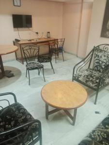 Una sala de estar con sillas y mesas y un televisor. en Hotel Valluvar, en Karūr