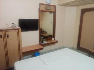 Habitación con espejo, TV y cama. en Hotel Valluvar, en Karūr 1 foto más