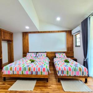 a room with two beds and a large screen at One Sa-Kaeo Homestay in Ban Non Chan