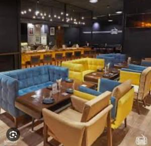 亭可马里Yash ViLLA的餐厅设有蓝色和黄色的椅子和桌子