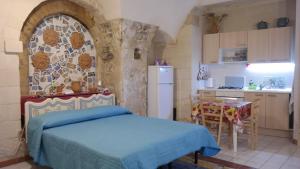 a bedroom with a blue bed and a kitchen at Casa MaFaCò in Modica