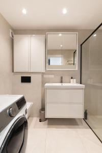 a bathroom with a white sink and a washing machine at Panorama City View Apartment in Vilnius +23 photos