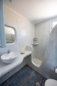 a white bathroom with a sink and a shower at Glaros Hotel (By The Sea) in Ios Chora