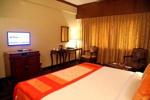 a hotel room with a bed and a television at Regent Park Hotel in Jalandhar