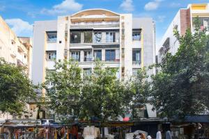 a tall white building with a tree in front of it at Hotel Royal Place in Kolkata