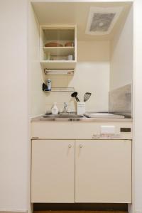 a kitchen with white cabinets and a sink at Minami-Ohashi Good Place House in Fukuoka