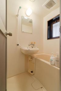 a white bathroom with a sink and a bath tub at Minami-Ohashi Good Place House in Fukuoka