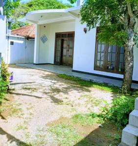 a white house with a tree in front of it at NOVA Guest in Mirissa