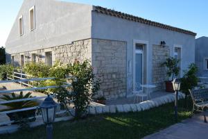 a white building with a table and a bench and a lamp at Azienda Agrituristica e Didattica CrauNari in Modica