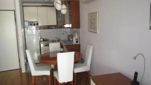 cocina con mesa de madera y sillas blancas en Apartment Marija, en Split