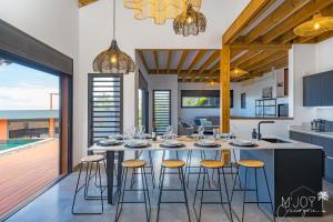a kitchen and dining room with a table and stools at KAZ BALEN***** Villa 10 pers à St-Leu in Le Portail