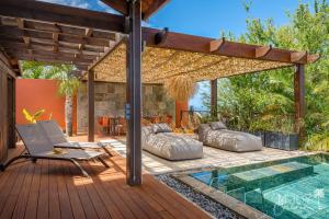an outdoor deck with a pool and a chair next to a house at KAZ BALEN***** Villa 10 pers à St-Leu in Le Portail