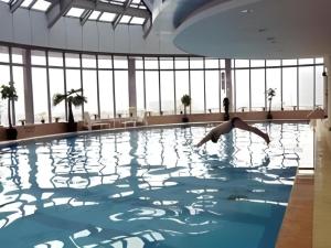 ZhaozhuangにあるZaozhuang Hotelの建物内のプールに飛び込む人
