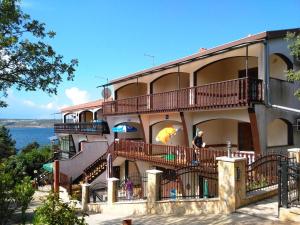 a building with balconies and a man holding an umbrella at Apartments Delfin in Posedarje
