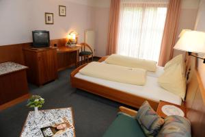 um pequeno quarto de hotel com uma cama e uma secretária em Hotel Edlingerwirt - Sauna & Golfsimulator inklusive em Spittal an der Drau