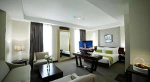 a living room with a couch and a bed in a room at PARK HOTEL Cawang Jakarta in Jakarta