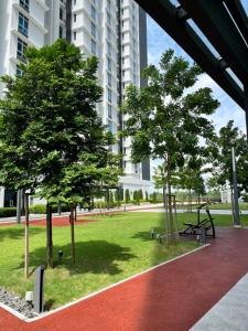 a park with trees and a bench in front of a building at Little Haven - Cozy 2BR with Big Swimming Pool in Kajang