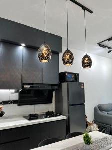 a kitchen with black cabinets and pendant lights at Little Haven - Cozy 2BR with Big Swimming Pool in Kajang