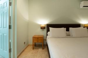 a bedroom with a white bed and a night stand at Mirah Villas in Denpasar