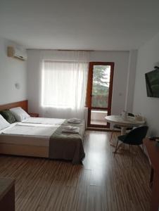 Un dormitorio con una cama y una mesa y una ventana. en Студио Аглая, en Varna