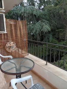 Una mesa de cristal y sillas en un balcón con árboles. en Студио Аглая, en Varna