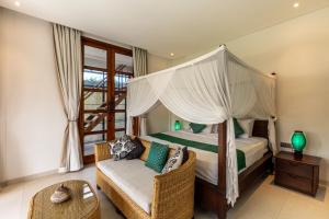 a bedroom with a canopy bed and a chair at Casa Doreena Villa by Betterplace in Munggu
