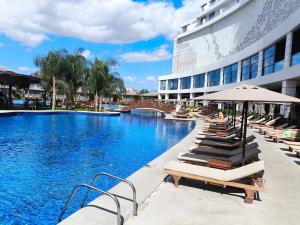 a pool with lounge chairs and umbrellas next to a building at Luxurious Apartments at Grand Sapphire Resort & Casino in Bahçeler