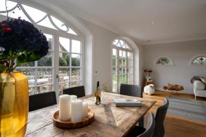 a dining room with a wooden table and some windows at Villa Hengist mit eigener Sauna, 600 Meter vom Weststrand, Wenningstedt, Sylt in Wenningstedt