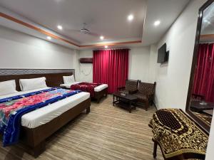Habitación de hotel con cama, silla, cama y sofá en Regent palaza, en Dargai