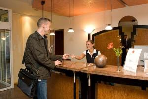 a man and a woman shaking hands at a counter at Hotel Erfurter Tor in Sömmerda