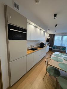 a kitchen with white cabinets and a table and a dining room at Triventi Mountain Residence Apartament Miętowy Zakątek in Karpacz