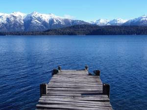 un muelle de madera en un lago con montañas cubiertas de nieve en La Torre de la Cascada, en Villa La Angostura