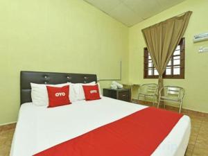 Un dormitorio con una cama grande con almohadas rojas y blancas. en Hotel O Saril Riverside HomestayNearLapangan Musara Alun, en Rawe 50 fotos más