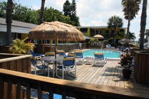 una terraza con mesa, sillas y piscina en Barefoot Bay Resort Motel, en Clearwater Beach