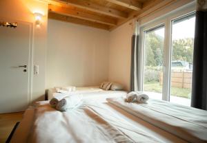 two beds in a room with a large window at S´Holzhäusle in Döbriach