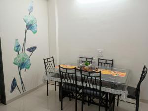 a dining room with a table and chairs with flowers on the wall at Pushpchhaya Home Stay in Nashik