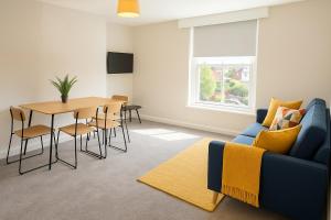 a living room with a blue couch and a table at Bright 2-Bed Top Floor Flat, Full Kitchen, Parking in Taunton