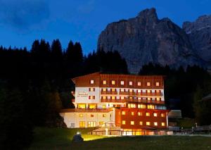 a large building in front of a mountain at night at Hotel Meisules in Selva di Val Gardena