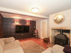 a living room with a fireplace and a flat screen tv at Yarn Cottage in Broadway