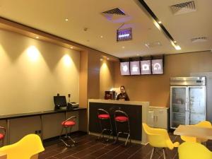 a woman sitting at a counter in a restaurant with yellow stools at IU Hotel Tianjin Fumin Qiao Branch in Tianjin