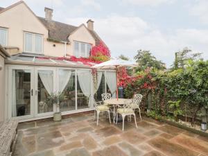 a conservatory with a table and chairs on a patio at Yarn Cottage in Broadway