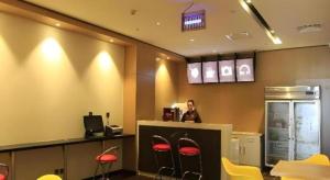 a woman standing at a counter with red stools at IU Hotel Tianjin Fumin Qiao Branch in Tianjin