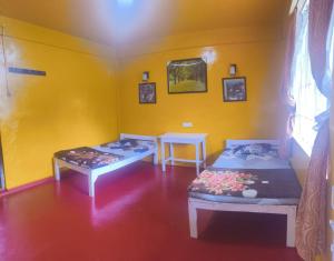 two beds in a room with a yellow wall at D Cloud Guesthouse in Cherrapunji