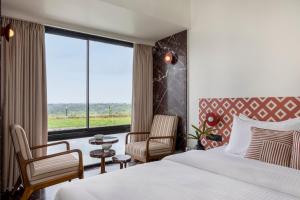 a hotel room with a bed and a large window at Scarlatta in Ghoti Budrukh +34 photos
