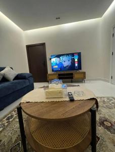 a living room with a table and a tv at شقة هادئة بصالة وغرفة نوم in Jeddah