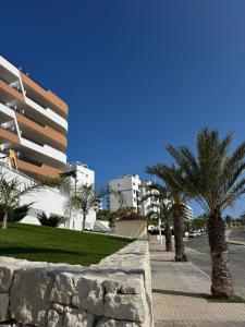 a street with palm trees and a building at Luxurious 2-Bedroom Apartment in Arenals del Sol with Pool and Sea Views in Arenales del Sol