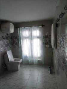 a bathroom with a toilet and a window at Snow Peaks View Home Stay in Gondla