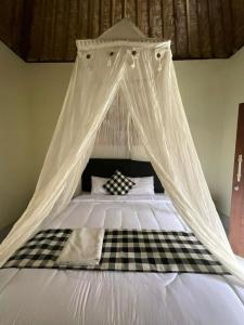 a bed with a canopy with a checkeredkered at Pondok Sayan Homestay in Ubud