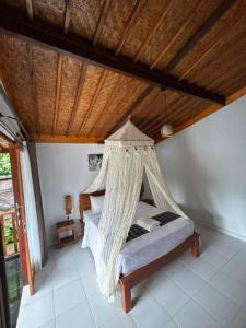 a bedroom with a bed with a mosquito net at Pondok Sayan Homestay in Ubud