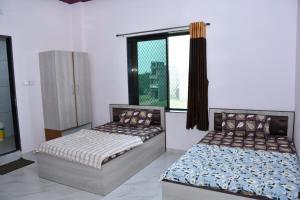 two beds in a room with a window at Hotel Khatushyamji in Rīngas